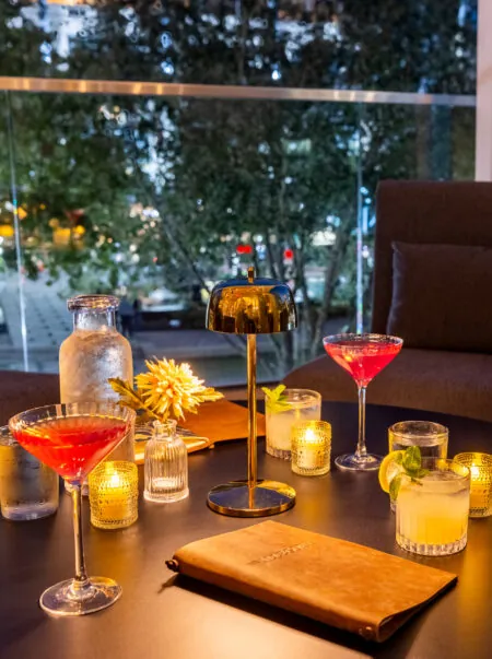 Table with assorted cocktails and drinks near a window.
