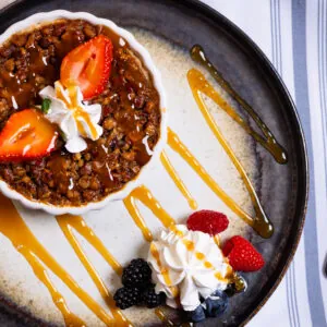 Dessert with whipped cream and strawberries on a plate, and caramel sauce.