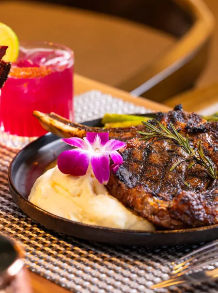 Steak with veggies and purple flower garnish.