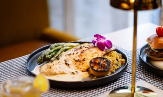 Plate with flatbread, grilled veggies and purple flower garnish.