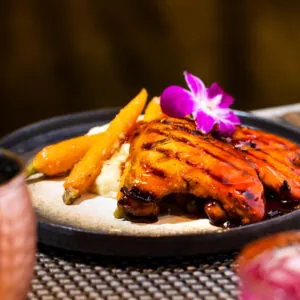 Meat with fries, rice and a purple flower on top.