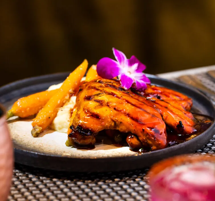 Meat with fries, rice and a purple flower on top.