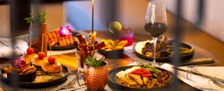 Dining table full of colorful dishes and wine glasses.