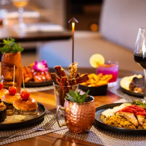 Table full of dishes and cocktails with flower garnishes.