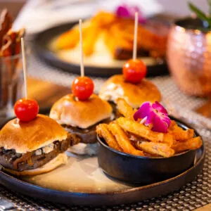 Mini burgers with fries and cherry tomatoes.