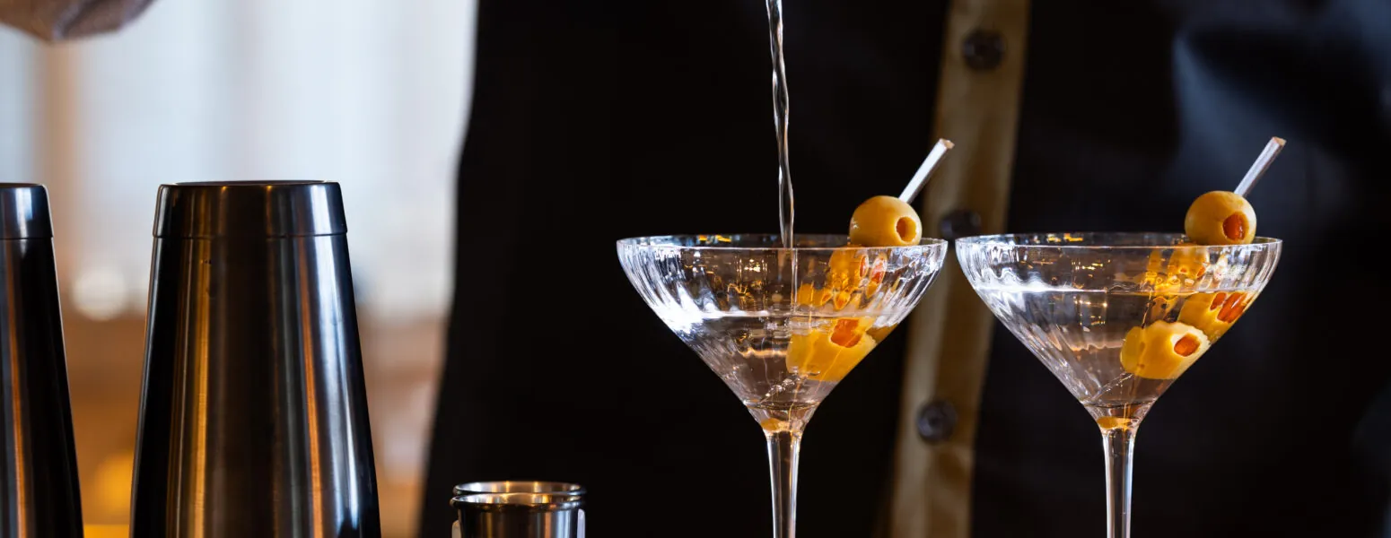 Bartender pouring martinis at the bar.