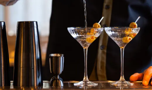 Bartender pouring martinis at the bar.